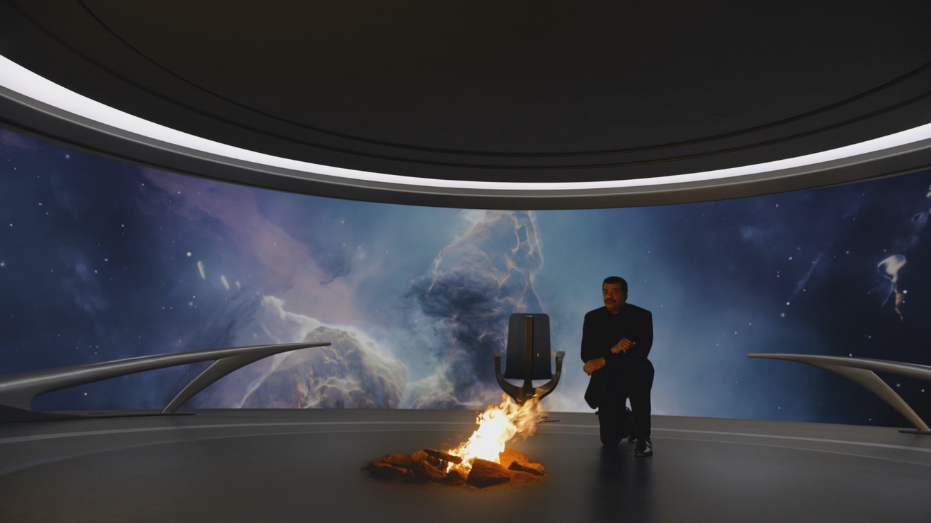 Host Neil deGrasse Tyson kneels before a fire on the Ship of the Imagination. Much as our ancestors used fire without understanding how it worked, we  have lived with the mystery of quantum physics for decades, while finding ways to exploit it. COSMOS: POSSIBLE WORLDS premieres March 9, 2020 on National Geographic. (Cosmos Studios)